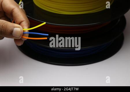 Drucker Filaments Spule horizontal gelegt mit drei verschiedenen Farben Filament in der Hand gehalten. Material, das aus Poly-Milchsäure namens PLA hergestellt wird Stockfoto
