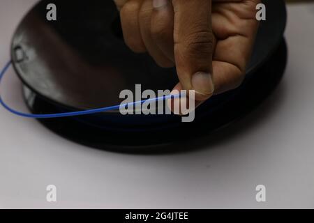 Blaues Filamentmaterial, das von einer Spule in der Hand gehalten wird. 3D-Drucker Verwenden Sie dieses Material, um Objekte mithilfe der fdm-Technologie zu erstellen Stockfoto