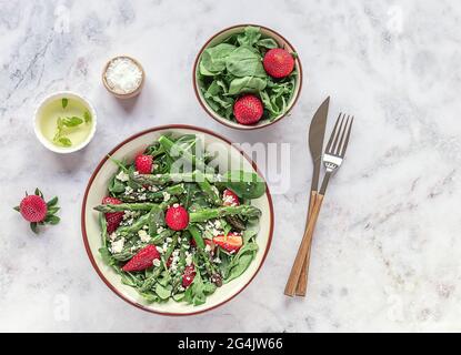 Köstlicher gesunder Salat aus frischen Erdbeeren, grünem Spargel, Feta-Käse, Rucola, Salat. Sauberes Essen, Lunchschüssel. Draufsicht. Stockfoto