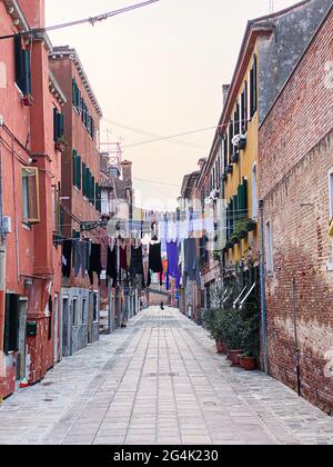 Bunte Sackgasse in Venedig mit viel Wäsche In den zwischen den Häusern gestreckten Linien zum Trocknen hingen Stockfoto