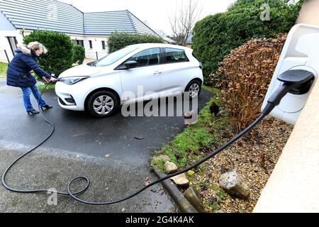 Renault Zoe Elektroauto. Frau lädt die Batterie ihres Fahrzeugs zu Hause auf Stockfoto