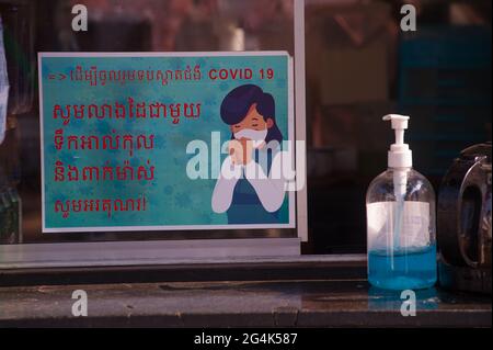 Während eines Ausbruchs von COVID - 19, stellt ein Unternehmen ein zweisprachiges Schild in Khmer-Schrift / Englisch Schreiben, das Menschen warnt, Gesichtsmasken auf dem Kandal Markt während der Coronavirus-Pandemie zu tragen. Phnom Penh, Kambodscha. März 2021. © Kraig Lieb Stockfoto