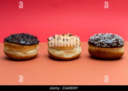 Köstliche glasierte Schokoladendonuts auf lebhaftem Hintergrund Stockfoto