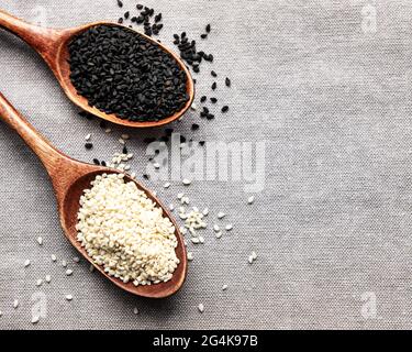 Gesundes Essen und Trinken Konzept. Schwarze und weiße Sesamsamen in einem Löffel auf einem textilen Hintergrund Stockfoto