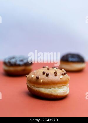 Köstliche glasierte Schokoladendonuts auf lebhaftem Hintergrund Stockfoto