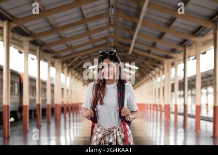 Porträt einer jungen Reisenden Frau mit kleinem Rucksack auf der Bahnstalle. Asiatische Frau Backpacker allein reisen Stockfoto