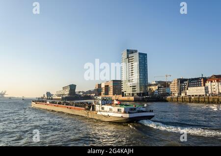 Malerische Uferpromenade und Industrieboot auf der Elbe in Hamburg, Deutschland Stockfoto