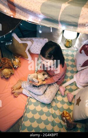 Draufsicht auf schöne Mädchen in Pyjamas spielen mit ausgestopften Tier in einem Tipi Stockfoto