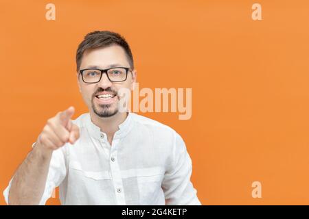 Fröhlicher kaukasischer Mann mit Brille über isoliertem Hintergrund, der die Finger auf die Kamera zeigt und ein fröhliches und lustiges Gesicht hat. Junger schöner Mann mit Bart wir Stockfoto