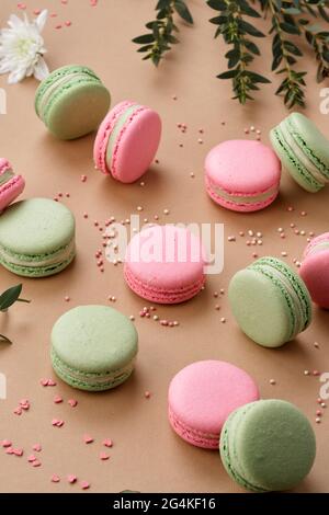 Macarons überraschend zarte grüne und rosa Farben, die ordentlich auf einem beigen Hintergrund angeordnet sind. Stockfoto