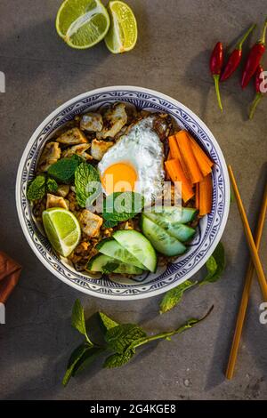Indonesischer Nasi Goreng gebratener Reis mit einem Spiegelei, frischer Gurke, Karotte, Minze, Limette und Chili Stockfoto