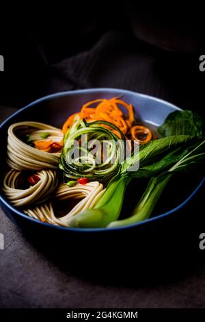 Rinderbrühe mit gestylten udon-Nudeln, Spiralgurke, Karotten und pak Choi Stockfoto
