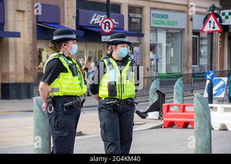 Sheffield UK: 17. April 2021: Zwei maskierte Polizistinnen überwachen die Straßen des Stadtzentrums von Sheffield, während es nach der Pandemie-Sperre wieder eröffnet wird. Stockfoto