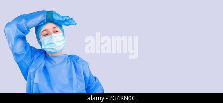 Banner, Langformat. Die Ärztin ist einer großen Anzahl von Patienten im Krankenhaus müde. Frau in einer medizinischen Ausrüstung hält ihren Kopf. Stockfoto