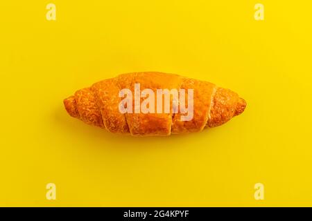 Ein einfaches Croissant, isoliert vor dem kolligen Hintergrund, traditionelles französisches Essen, Minimalismus-Konzept Stockfoto