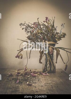 Verwelkt Blumen Bouquet in einer klaren Glasvase, Vintage gefiltert Stockfoto