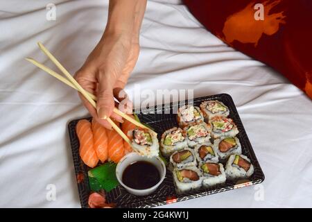 Lady isst Sushi mit Essstäbchen Stockfoto