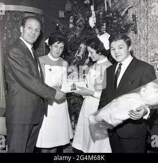 Der berühmte britische Boxmeister Henry Cooper und der ehemalige Olympiasieger und britische Featherwight-Champion Terry Spinks aus den 1960er-Jahren besuchten ein Krankenhaus in Lewisham, Southeast London, England, Großbritannien, und überreichen zwei Krankenschwestern einen Kuchen. Henry Copper wurde zu einer berühmten Figur im britischen Sport, nachdem er den legendären amerikanischen Boxer Muhammed Ali auf die Leinwand klopfte und war einer der ersten, der vom Wachstum der Sport-Promi-Branche profitieren konnte und sich zu einem bekannten Namen für große Verbrauchermarken entwickelte. Stockfoto