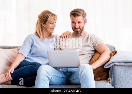 Aufnahme eines hübschen Paares, das sich zu Hause auf der Couch entspannt und einen Laptop benutzt, während man im Internet surft. Stockfoto