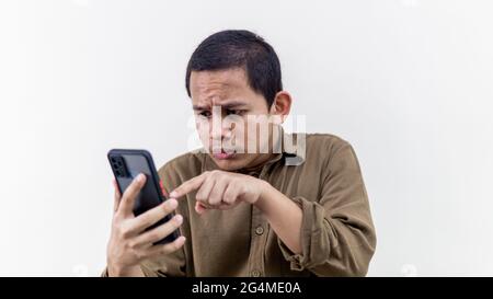 Junge asiatische Malaiisch Probleme mit der Verwendung eines Smartphones auf weißem Hintergrund Stockfoto