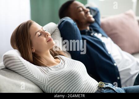 Entspannendes Konzept. Junge Interracial Paar Zusammen Ruhen Auf Bequemen Sofa Zu Hause Stockfoto