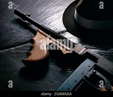 Mafia noch Leben, Rauchen Thompson Sub Maschinengewehr und Hut auf kalten nassen Schiefer Stockfoto