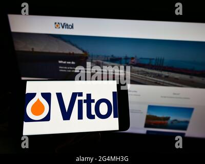 Person, die ein Mobiltelefon mit dem Logo der niederländischen Handelsgesellschaft Vitol Holding B.V. auf dem Bildschirm vor der Unternehmenswebseite hält. Konzentrieren Sie sich auf die Telefonanzeige. Stockfoto