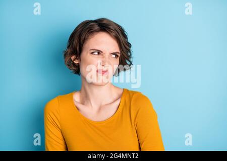 Foto von Annoy schöne Brünette kurze Frisur Dame suchen leeren Raum tragen braunes Hemd isoliert auf hellblauen Hintergrund Stockfoto