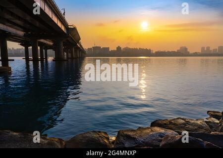 Wunderschöne koreanische Sommerlandschaft in Seoul. Brücke, die den Hangang River in Seoul verbindet, wunderschöner Sonnenaufgang über dem Gebäude. Stockfoto