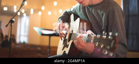 Junger Mann, der auf akustischer Gitarre spielt Stockfoto