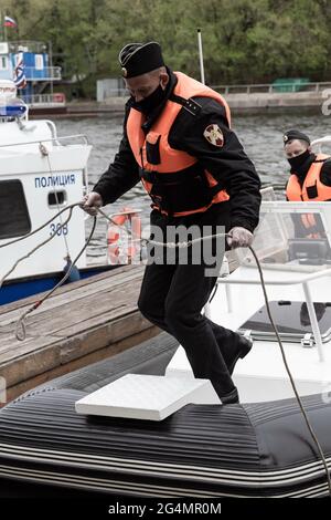 10. Mai 2020, Moskau, Russland: Ein Segler der russischen Nationalgarde hilft, ein Patrouillenboot am Pier zu parken.im Frühjahr 2020 wurden aufgrund des Ausbruchs einer neuen Coronavirus-Infektion in Moskau anti-epidemiologische Maßnahmen eingeführt. Ohne unnötige Notwendigkeit wurde den Bürgern geraten, nicht an öffentliche Orte zu gehen, und alle Bewegungen in der Stadt mussten mit medizinischer Schutzausrüstung und mit einem elektronischen Pass durchgeführt werden. Die Durchsetzung restriktiver Maßnahmen auf den Straßen der Stadt wurde von der Polizei und der Nationalgarde überwacht. Flussboote, Drohnen und Ka-226-Hubschrauber wurden eingesetzt Stockfoto