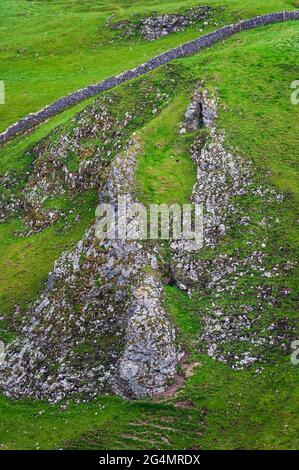 Blick nach Osten in Richtung Hope Valley durch hohe Riffkalkplatten am Winnats Pass, einer tiefen Einschnittschlucht in Castleton, Hope Valley. Stockfoto