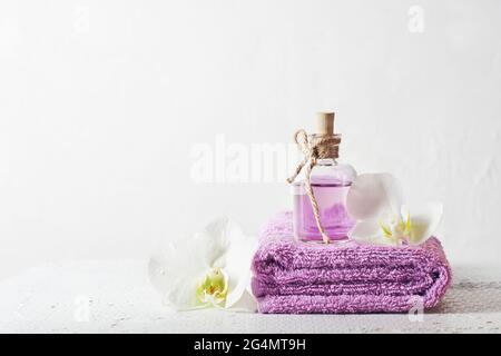 Eine Flasche Fliederduft und Orchideenblumen. Aromatisches kosmetisches Produkt, Spa-Behandlungen. Stockfoto