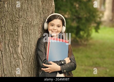 Mädchen hören Audio tragen Lehrbücher entspannend Park Hintergrund, Sound in ihrem Kopf Konzept Stockfoto