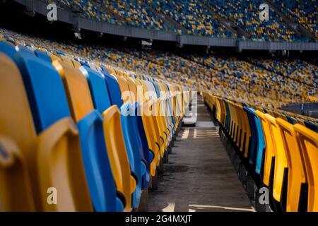 Leere Sitzreihen in einem Fußballstadion mit gelben und blauen Bänken Stockfoto