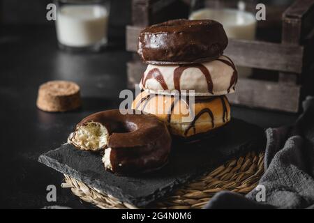 Vertikale Aufnahme eines Stapels Donuts mit Schokolade und Karamell-Zuckerguss auf einem schwarz dekorierten Tisch Stockfoto