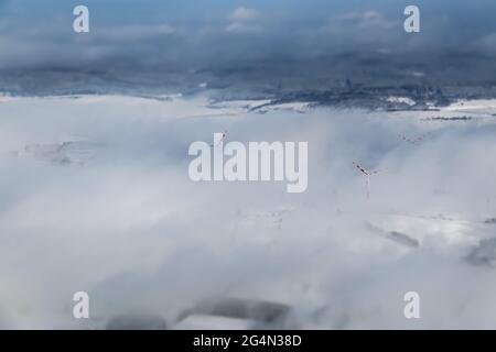 Windmühlen, die sich während eines winterlichen Morgens im Nebel verstecken Stockfoto