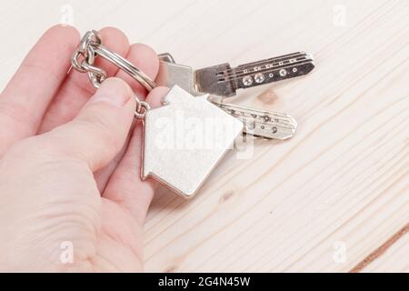 Hand hält Schlüssel mit Haus geformten Schlüsselanhänger mit Kopierraum Stockfoto