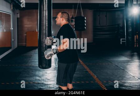 Junge Muskel Boxer mit einem Boxsack in der Turnhalle. Boxer schlagen Stanzgeschwindigkeit Tasche Stockfoto