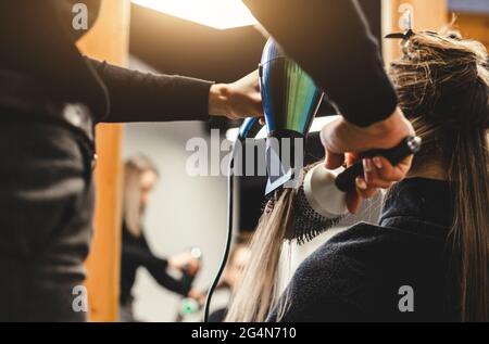 Friseurmeisterin trocknet die Haare des Mädchens nach dem Waschen in einem Schönheitssalon mit einem Haartrockner. Stockfoto