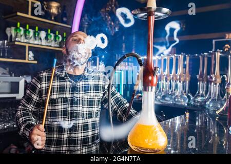 Mann, der in einem Nachtclub traditionelle Shisha raucht Stockfoto