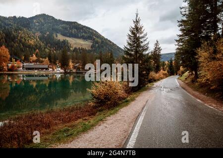 Landschaft mit Straße entlang See und Besiedlung Reflexion auf Herbstsaison in den Dolomiten, Italien Stockfoto