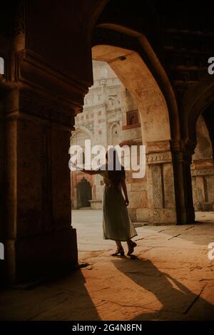 Ganzkörper-Rückansicht einer anonymen Touristenattraktion, die unter einer gewölbten Passage des Muhammad Shah Sayyid-Grabes im Lodhi Garden in Neu-Delhi steht Stockfoto