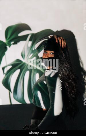 Rückansicht einer ethnischen Frau in Kopfhörern, die am Tisch sitzt Mit Mischpult und Sprechen im Mikrofon während der Arbeit in Sendestudio Stockfoto