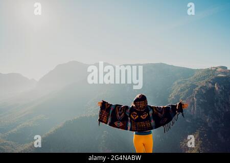 Fröhlicher Mann in lässiger Kleidung, der an sonnigen Tagen gegen die Plantage von Marihuana steht, das im Gewächshaus wächst Stockfoto