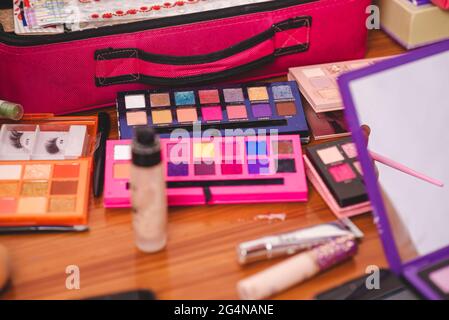 Von oben Paletten von bunten hellen Lidschatten in der Nähe von verschiedenen Kosmetik-Zubehör auf dem Tisch im Studio platziert Stockfoto