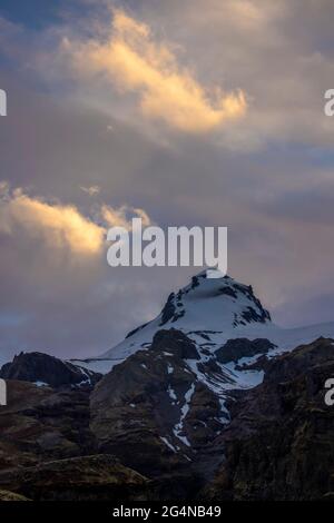 Niedriger Winkel der Bergspitze mit Schnee bedeckt und gegen bewölkten Himmel am Morgen in Island Stockfoto