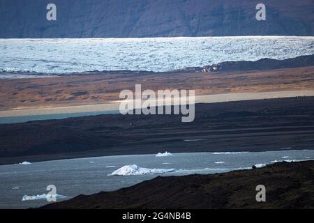 Eisschollen, die am Frühlingstag in Island auf dem Wasser des Flusses in der Nähe rauer Ufer schwimmen Stockfoto