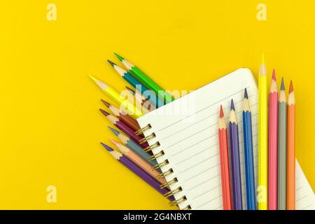 Back to School Komposition mit Notizblock und Farbstiften, Bildungskonzept, gelber Desktop-Hintergrund, Draufsicht Stockfoto