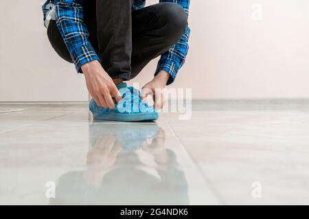 Die Hände der Person legten sich die blauen Schuhüberzüge an den schmutzigen Turnschuhen im Krankenhaus an Stockfoto